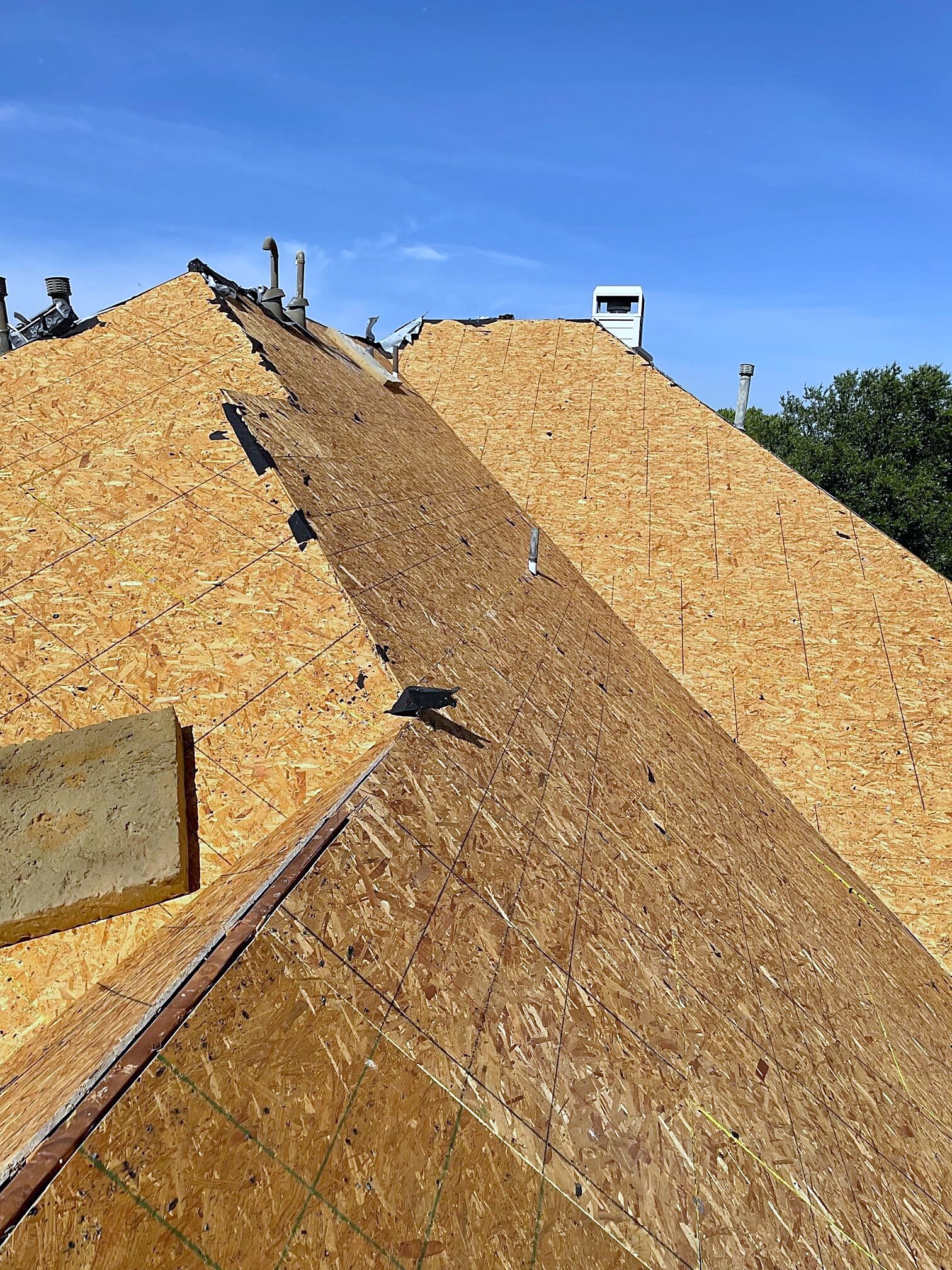 Bare plywood decking up to the ridge after a tear-off