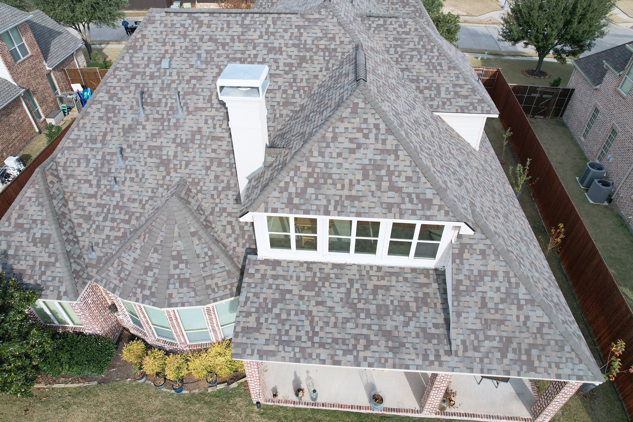Drone view looking down on a two-story home with a new hip roof and a dormer