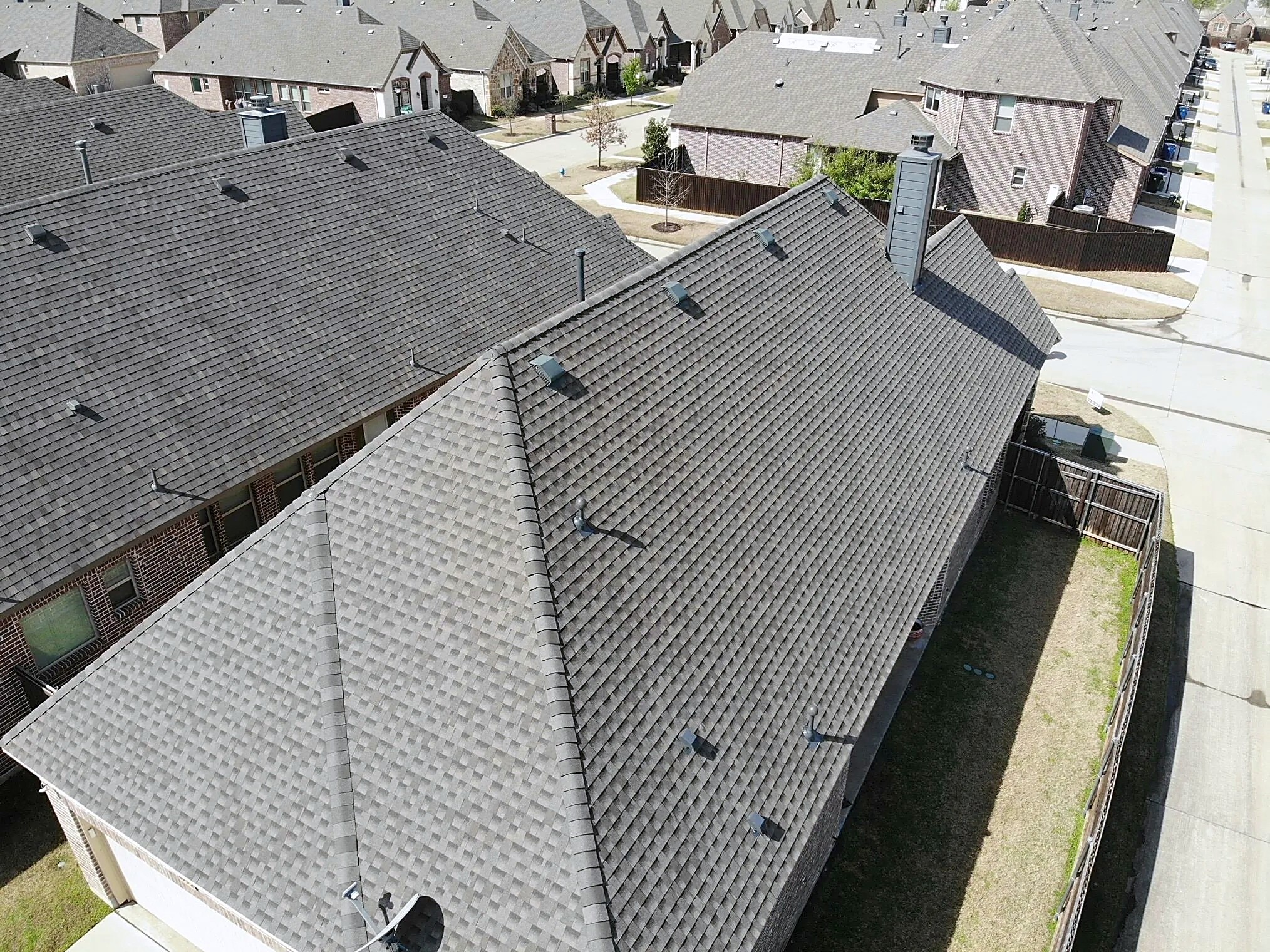 Aerial view of a new shingle roof over a two-story home on a curving street