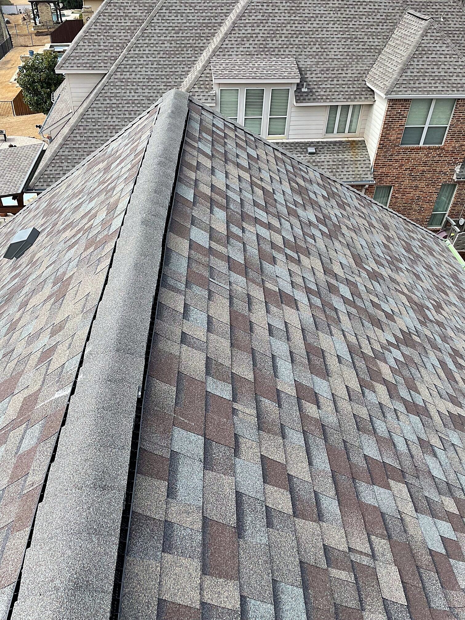 A finished architectural shingle slope running up to the ridge