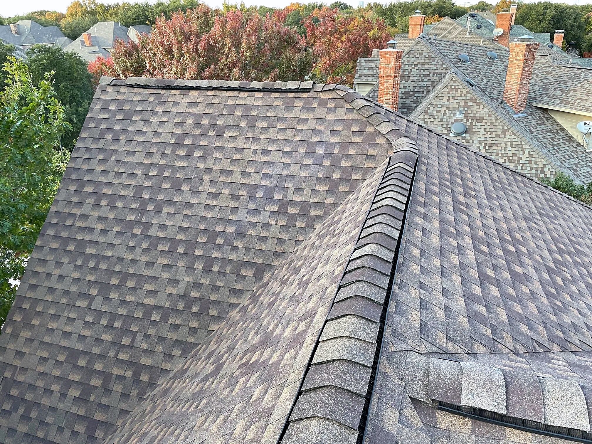 New shingles and a high-profile ridge with red autumn trees behind
