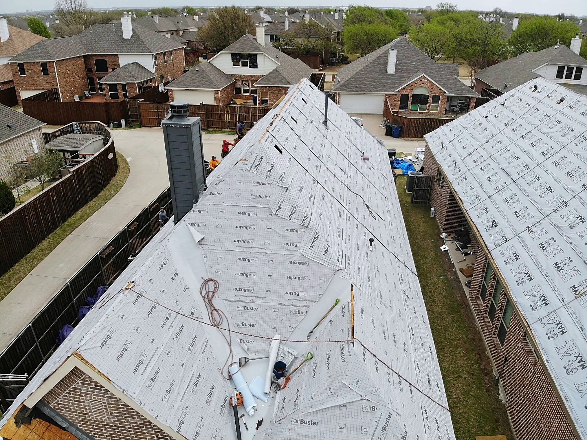 Rows of new synthetic underlayment across a roof, seen from a drone